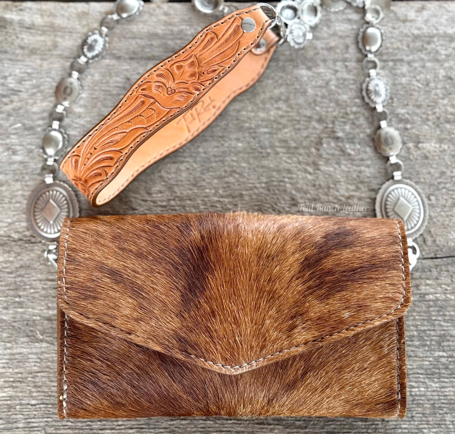 Small hair on hide cross body purse with tooled leather strap and concho chain