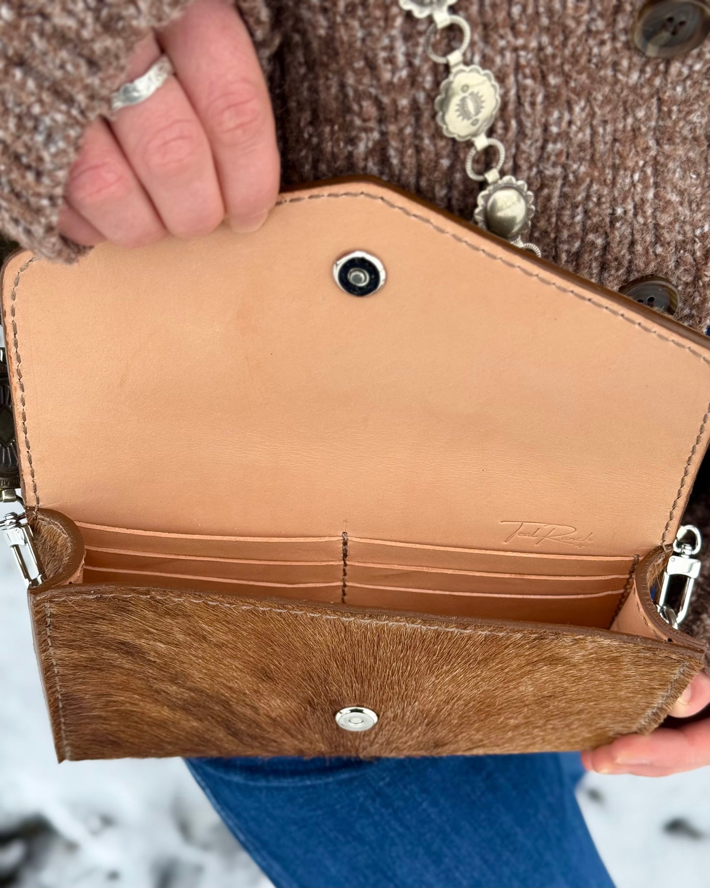 Small hair on hide cross body purse with tooled leather strap and concho chain